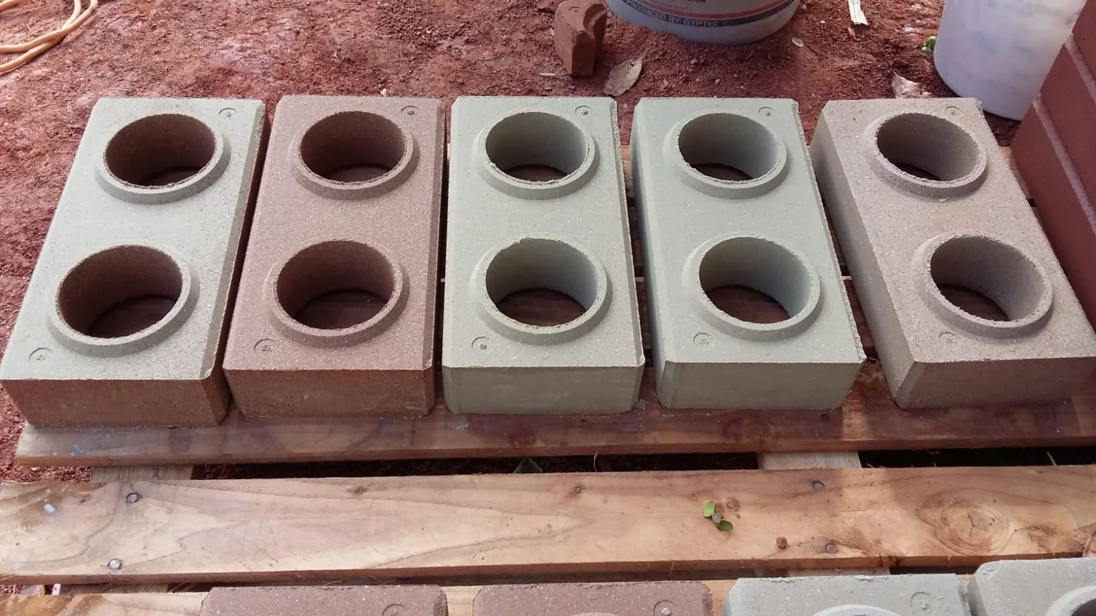 Cinco ladrillos ecológicos en tonos terracota, arena y gris verdoso sobre una paleta