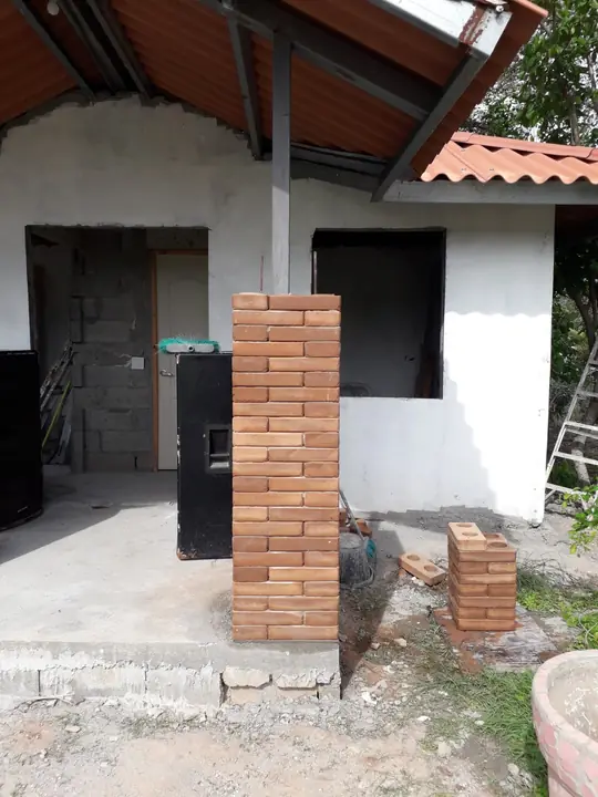 Columna de ladrillo ecológico terracota junto a una casa en construcción