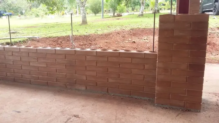 Muro de ladrillo ecológico con varillas de acero saliendo de los orificios